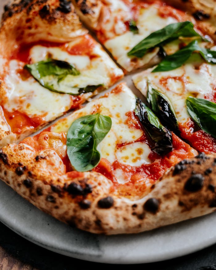 Close-up of a Neapolitan pizza with fresh basil leaves and melted cheese, perfect for food enthusiasts